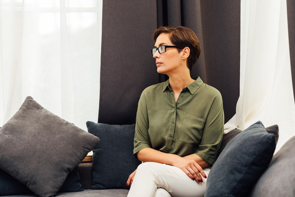Woman looking to the side sitting on sofa with pillow