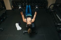 Woman lifting dumbbells on bench