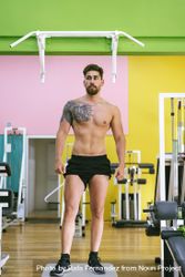 Front of man standing under pull up bar in colorful gym 0VZ1r0