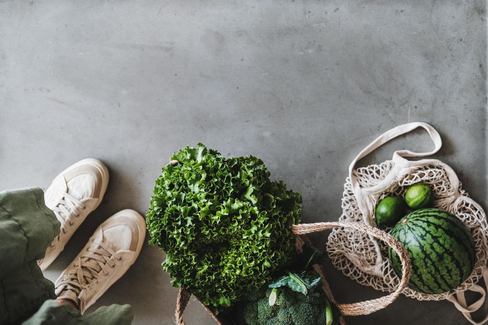 Overhead shot of grocery shopping jute full of fresh produce, with shoes, mesh bag, copy space