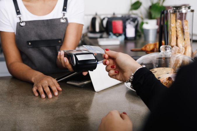 Woman tapping credit card on payment machine in cafe