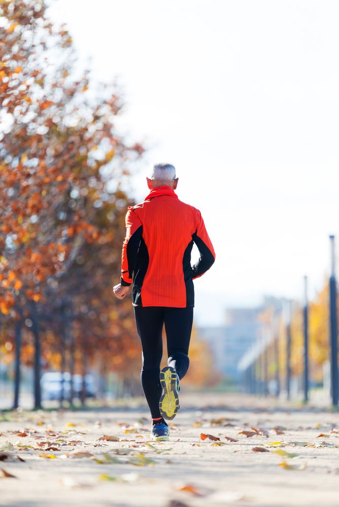 Back of male in red wind breaking running in park