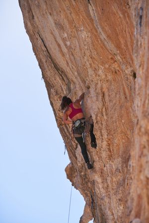 Unrecognizable woman climbing mountain wearing activewear