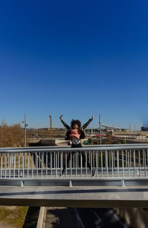 Woman with afro hair jumping for joy in the streets.