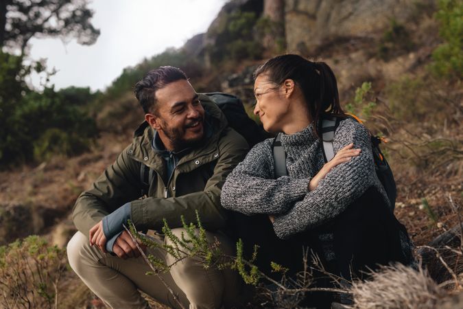 Couple taking a break on a hike smiling and looking at each other