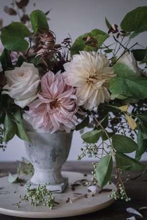 Composition of flowers and plants in vintage vase on board