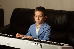 Young boy looking up while playing piano.
