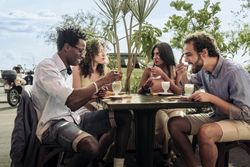Group of diverse friends eating dessert at an outdoor cafe in Italy