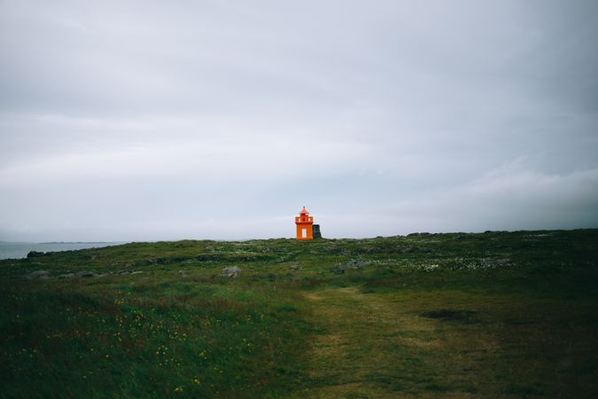 Solitary orange lighthouse on cloudy day