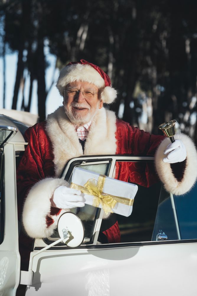 Cheerful Santa Claus in van with gift and bell