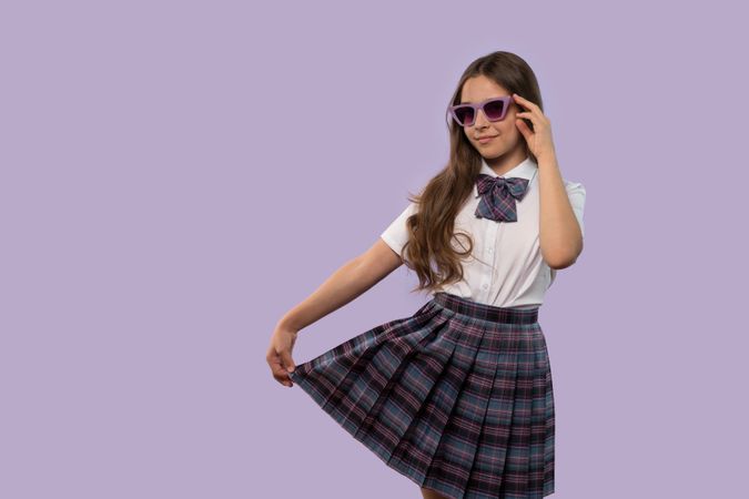 Young girl holding skirt while posing confidently
