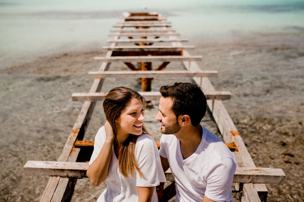 Glad lovers sitting on destroyed pier on seashore