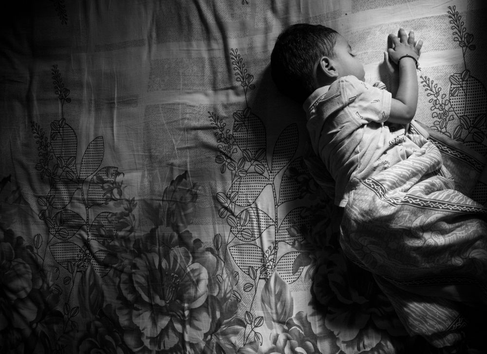Grayscale photo of toddler sleeping on bed