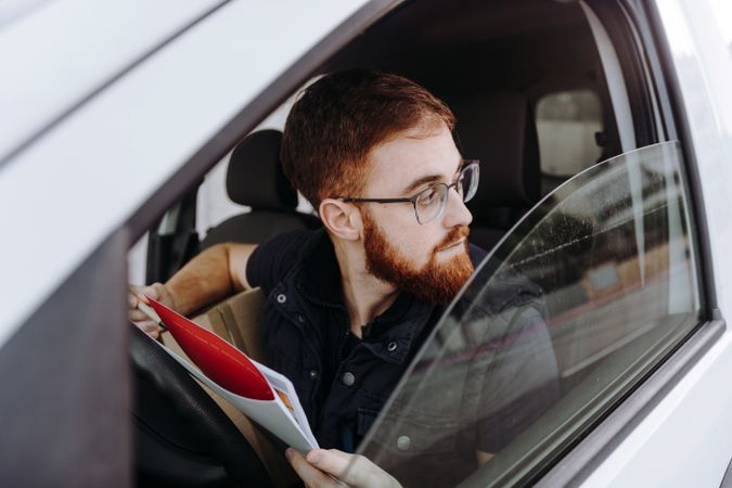 Courier filling papers while preparing for delivery of order to client in car