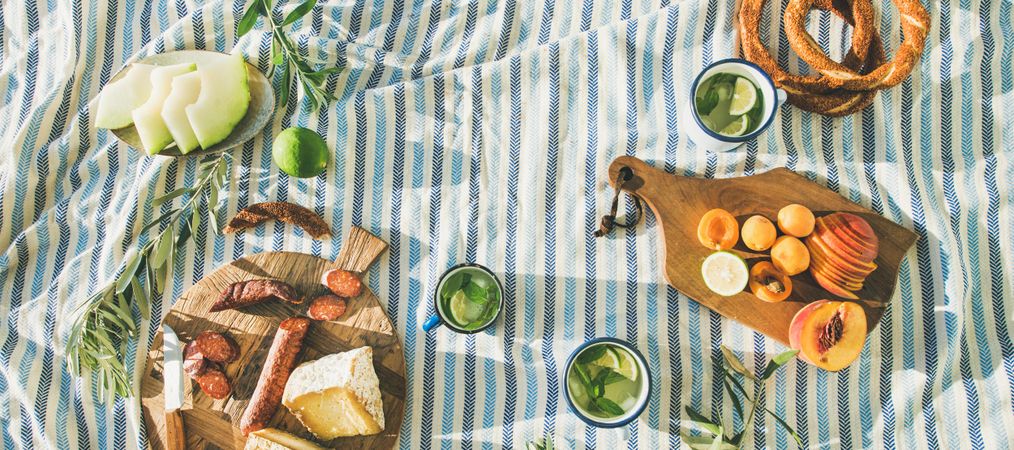 Summer picnic spread with pretzels, mojitos, meat and cheese board