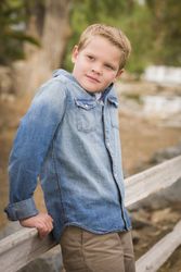 Handsome Young Boy Against Fence in Park