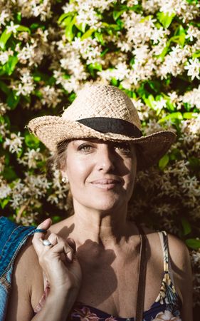 Woman standing near a wall with flower shrubs