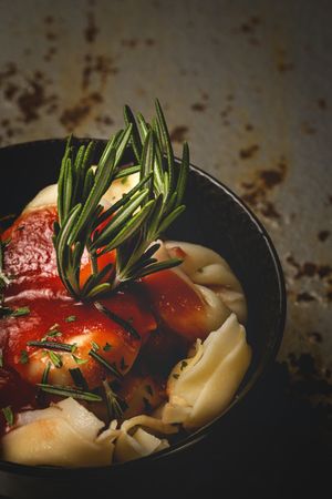 Plate of delicious ravioli with tomato sauce served on table