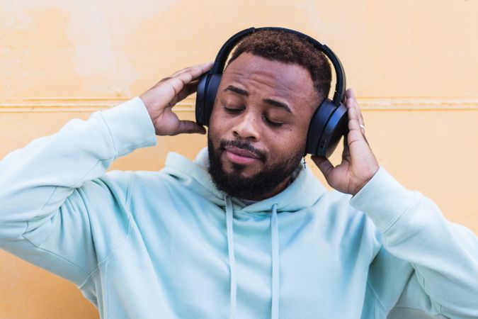 Optimistic Black hipster listening to music with headphones