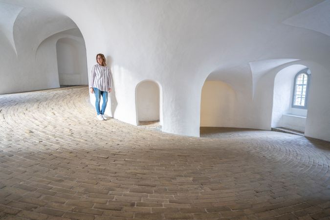 Casual woman leaning on wall in spacious gallery with windows