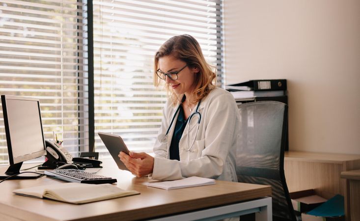 Female doctor using a digital tablet at her desk in the clinic