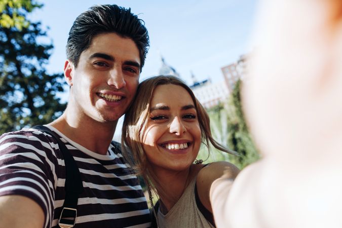 Happy young couple taking selfie in park
