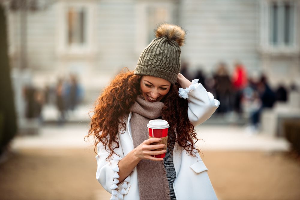 Woman drinking coffee wandering in the streets of Madrid on winter