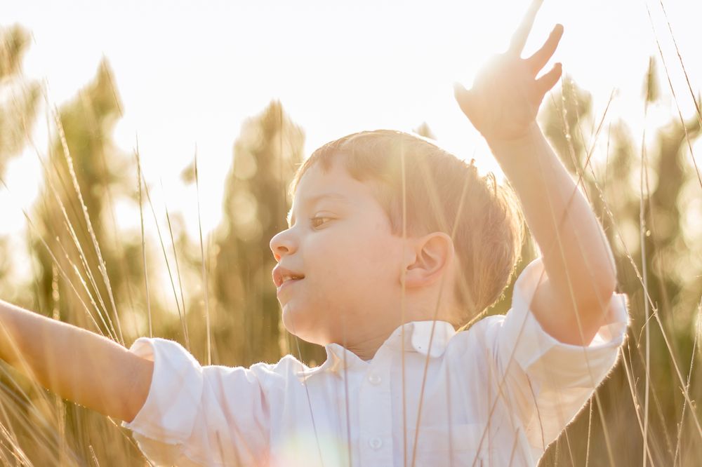 Kid in field playing with spikes at summer sunset