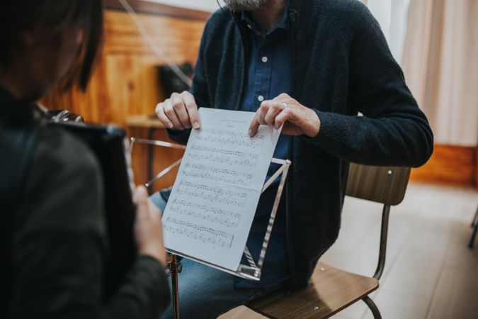 Teacher holding sheet music in front of student