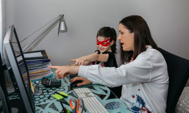 Woman teleworking with daughter showing her a drawing