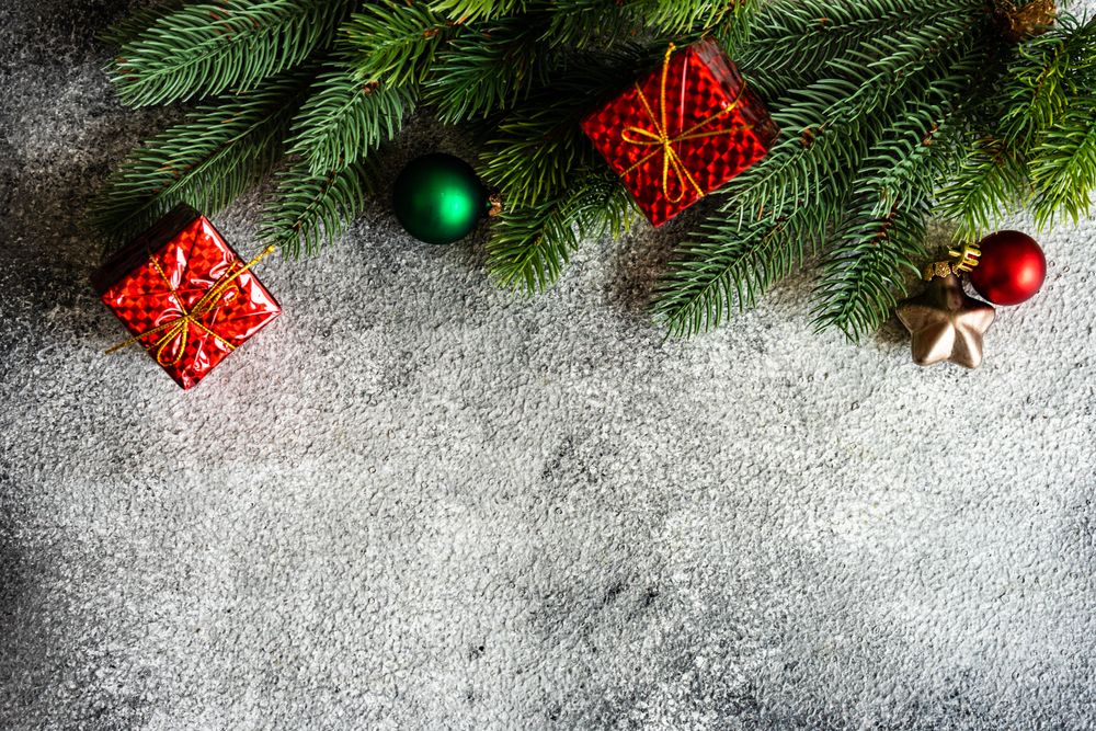 Christmas frame with pine and gift boxes on stone background