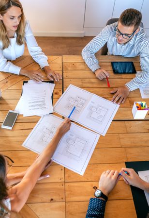 Top view of architects in a work meeting looking at construction drawings