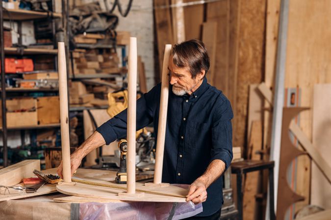 Man measuring wooden table in studio