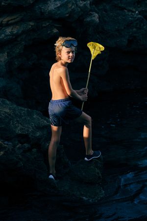 Boy in swimming trunks with net in mountains
