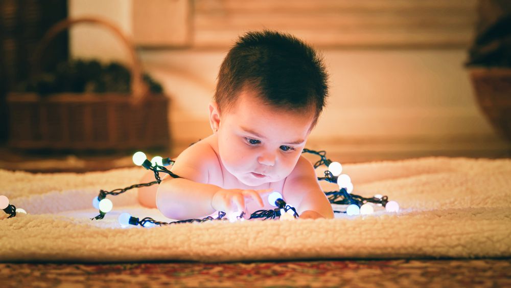 Baby playing with light garland on Christmas Day