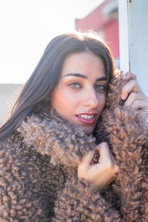 Cheerful woman wrapping in coat on street