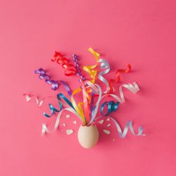 Egg with party streamers on pink background