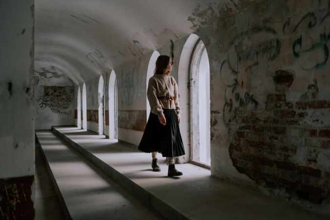 Young woman walking in hallway looking at the window