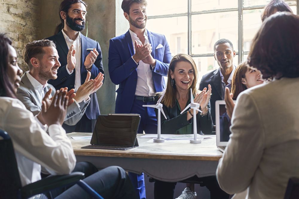 Group of multiethnic coworkers applauding the success of a sustainability project