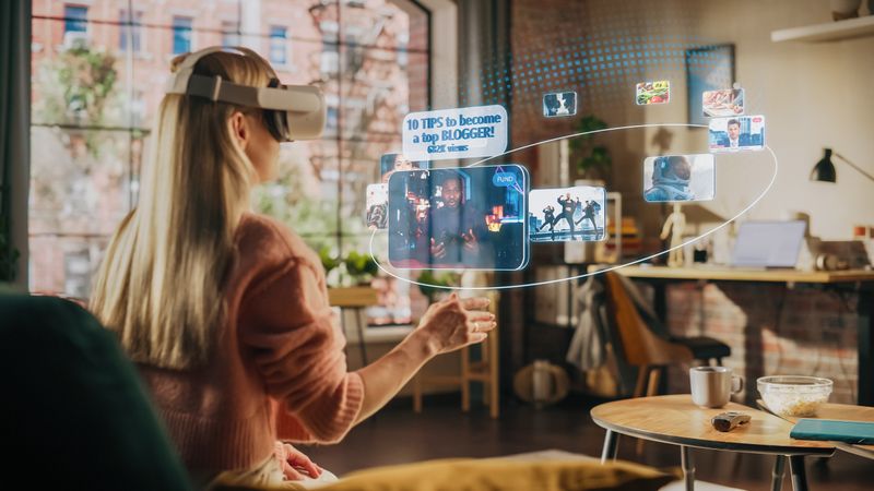 Woman Sitting in Loft Living Room at Home, Using Virtual Reality Headset with Controllers to Check Social Media Streaming App