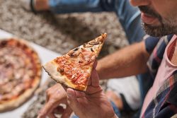 Anonymous male eating delicious pizza