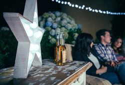 Star lamp with light bulbs over table with beer bottles