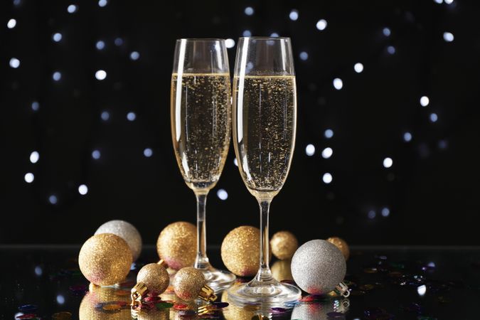 Christmas baubles and champagne glasses on blurred background, copy space