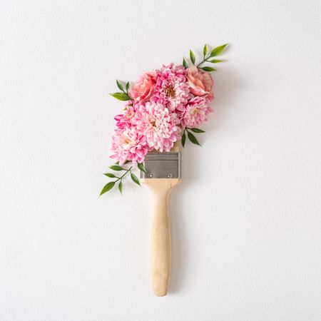 Layout made of flowers and paint brush on light background