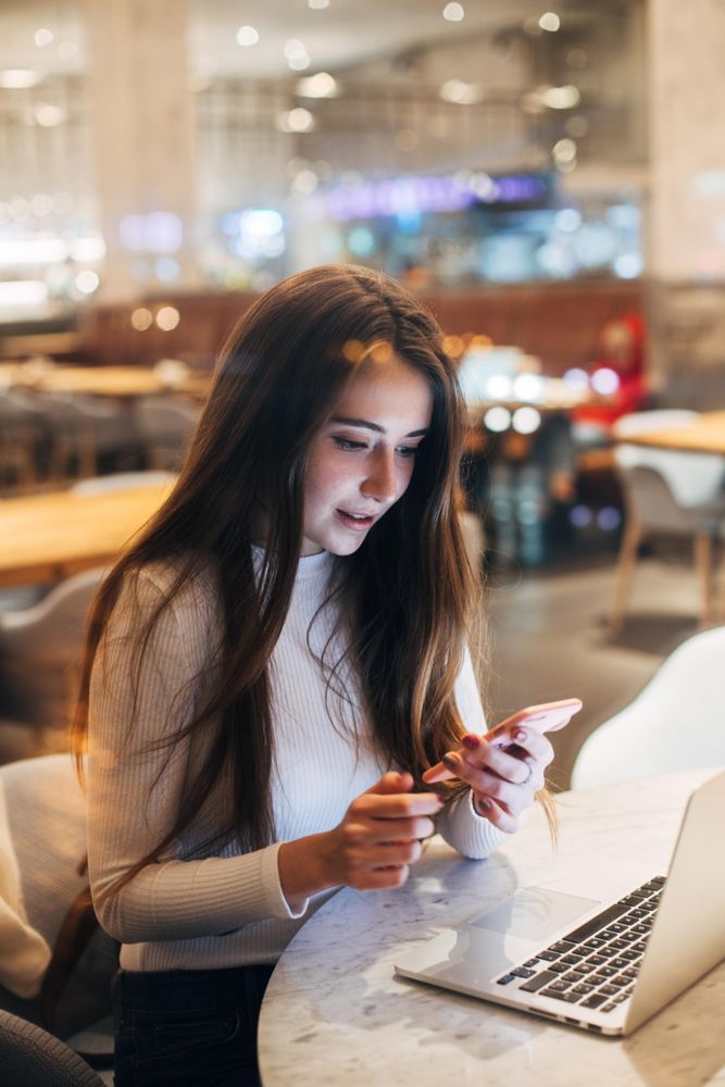 Young brunette woman looking surprised while looking at her smart phone
