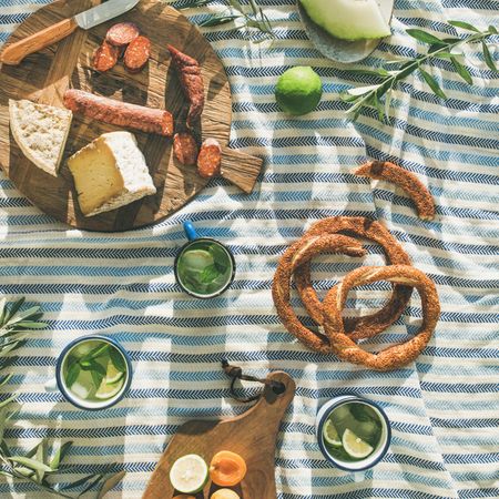 Summer picnic spread with pretzels, mojitos, meat and cheese board