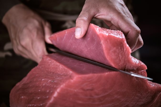 Male hands of a chef cutting a delicious loin of fresh bluefin t