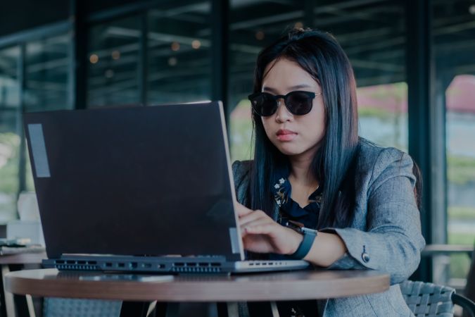 Dedicated freelancer coding remotely in modern cafe with sunglasses