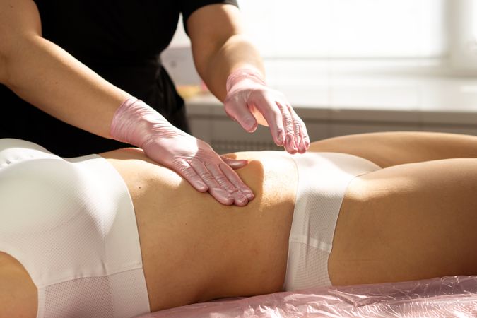 Therapist massages honey into abdomen during spa body session.
