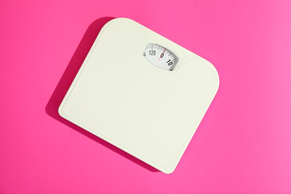 weigh scales on pink background, space for text